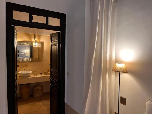 马拉喀什RIAD ENNAFOURA BOUTIQUE HOTEL的一间带水槽、镜子和门的浴室