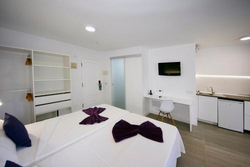 拉克鲁斯Skyview Hotel Tenerife的白色卧室配有一张大白色床和紫色的弓
