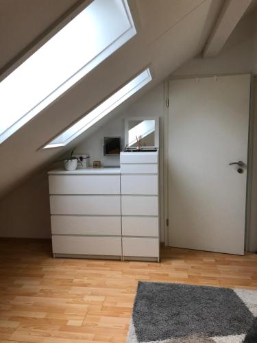 BirmensdorfZurich Studio的阁楼厨房配有天窗和白色橱柜。