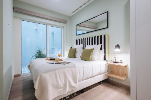 塞维利亚Sercotel Sevilla Guadalquivir Suites的卧室设有一张大白色的床和大窗户
