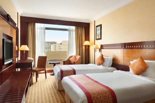利雅德Ramada by Wyndham Hotel Riyadh的酒店客房设有两张床和电视。