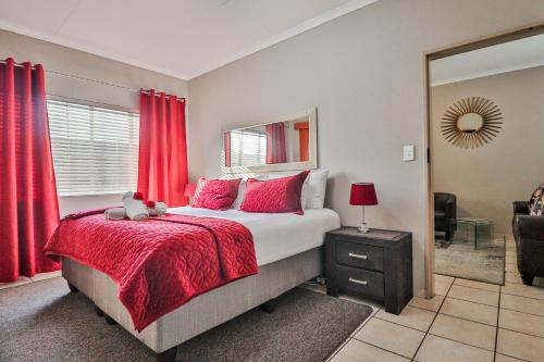 博克斯堡Rudman Townhouses - OR Tambo Airport的一间卧室配有一张带红色窗帘的大床