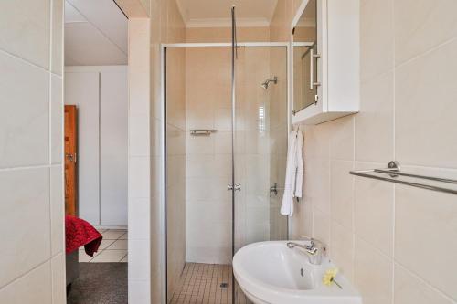 博克斯堡Rudman Townhouses - OR Tambo Airport的带淋浴和盥洗盆的白色浴室