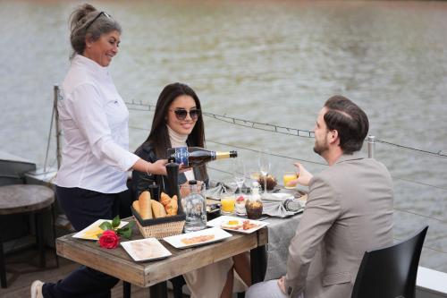 科特赖克Hotel Restaurant Brasserie Feestzaal Ahoi, Kortrijk的船上的女人把酒倒在桌子上