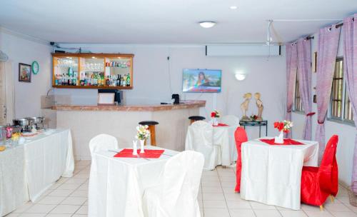 利伯维尔Hotel Hibiscus Blvd Triomphal的一间设有白色桌子和红色椅子的餐厅