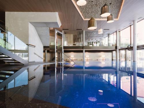 纳图尔诺Lindenhof Pure Luxury & Spa DolceVita Resort的一座蓝色海水室内游泳池,位于一座建筑中