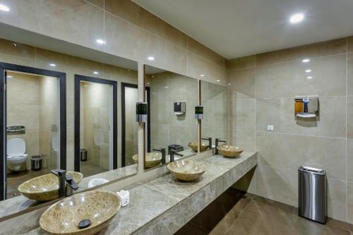 特马Alisa Hotel Tema的一间带三个水槽和镜子的浴室