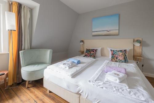 圣彼得奥尔丁Hotel 'Das Strandhaus'的卧室配有白色的床和椅子