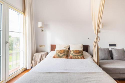 埃尔罗西奥GINVA - Apartahotel El Rocio-Doñana的一间卧室配有带两个枕头的床和一张沙发
