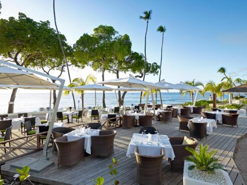 圣詹姆斯Tamarind by Elegant Hotels - All-Inclusive的海滩上的餐厅,配有桌子和遮阳伞