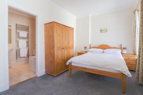 伊林港Falcon's Nest Hotel的一间卧室配有一张床和一个木制橱柜