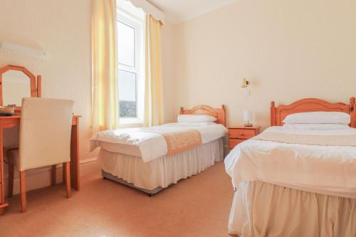 伊林港Falcon's Nest Hotel的一间卧室设有两张床、一张桌子和一个窗口。