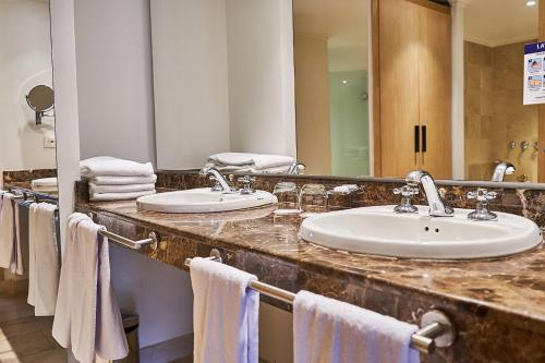 麦德林波普拉多广场酒店的浴室设有2个水槽、镜子和毛巾。