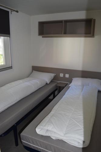 加斯泰Mobilhome 526 3ch/2SDB camping 4* La Réserve SIBLU Gastes的两张床位于带窗户的房间内