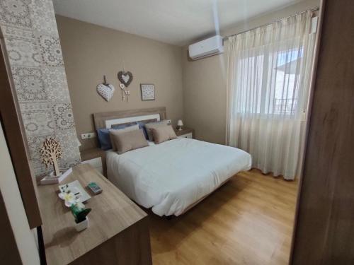 拉苏维亚Ático Granada al Sol (terraza vistas montaña)的一间卧室配有一张床、一张桌子和一个窗户。
