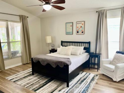 布雷登顿Sandy Oasis 5 bedroom with Pool Sarasota Bradenton的卧室配有1张床、吊扇和1把椅子