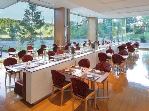 成田成田全日空皇冠假日酒店的餐厅设有桌椅和窗户。