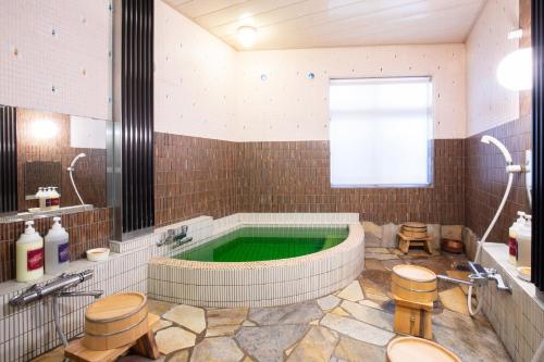 高冈市大佛日式旅馆的带浴缸的大型浴室,设有绿色游泳池