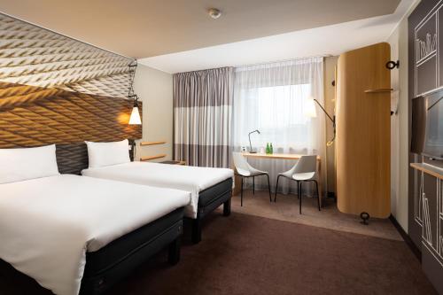波兹南Ibis Poznan Centrum的酒店客房设有两张床和一张桌子。