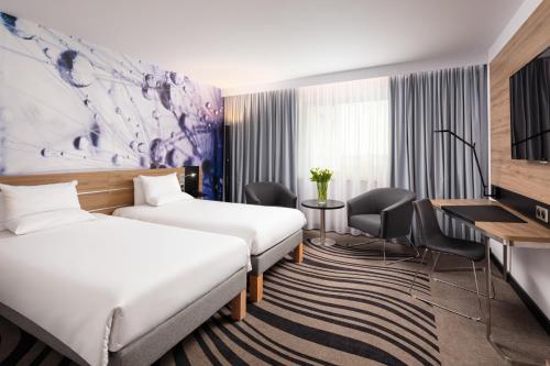 波兹南诺富特波兹南中心酒店的酒店客房配有两张床和一张书桌
