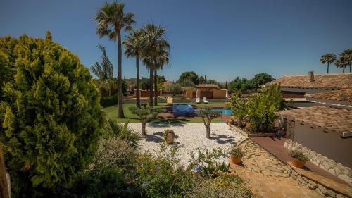 布索特Hotel Boutique Canelobre的一个带游泳池、棕榈树和房子的后院