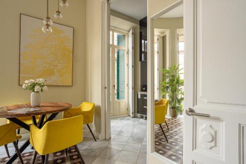马拉加Madeinterranea Apartments的一间带桌子和黄色椅子的用餐室