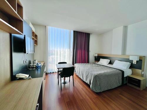 北尼科西亚Sky Roof Hotel的配有一张床、一张桌子和一张桌子的酒店客房