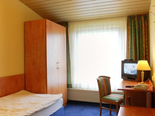 埃尔姆山麓克尼格斯卢特尔克恩纳斯登酒店的一间卧室设有一张床、一台电视和一个窗口。