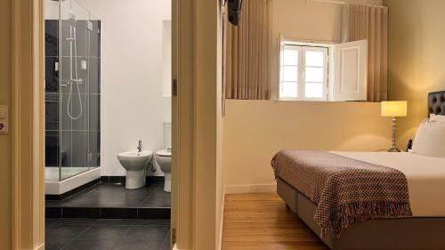 里斯本莎杜卡萨杜拜鲁旅馆的一间卧室配有一张床,浴室设有淋浴。