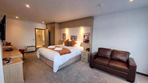 卡迪根The Teifi Waterside Hotel的一间卧室配有一张床和一张皮沙发