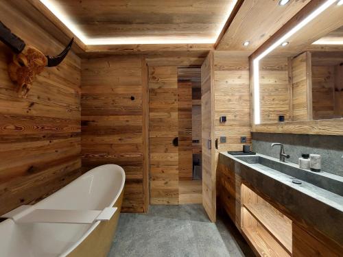夏蒙尼-勃朗峰卡尔兹蒙布兰科酒店的一间带木墙、浴缸和水槽的浴室