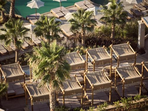 阿齐亚佩拉加Seaside A Lifestyle Resort - Adults Only的一组木椅和棕榈树