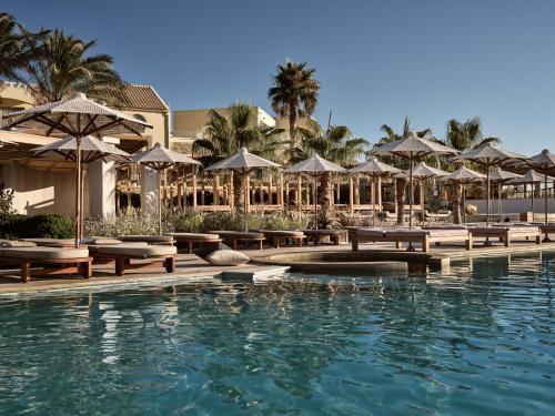 阿齐亚佩拉加Seaside A Lifestyle Resort - Adults Only的一个带桌子和遮阳伞的度假游泳池
