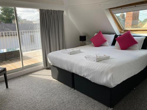 纽马基特Kings Lodge的一间卧室配有带粉红色枕头的床和窗户。