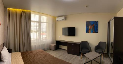 波尔塔瓦Hotel Atmosphere的一间卧室配有一张床和一张带两把椅子的桌子