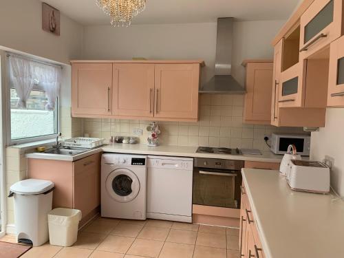 利Starlight Self Service Accommodation的厨房配有木制橱柜、洗衣机和烘干机