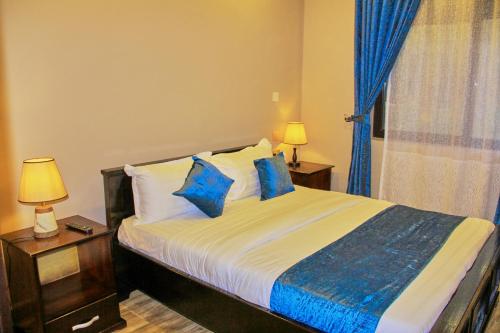 HoimaGolden Castle Hotel Hoima的一间卧室配有一张带蓝色枕头的床和一扇窗户。