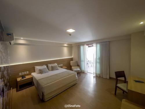 佩德拉阿祖尔Vista Azul Hotel的配有一张床和一把椅子的酒店客房