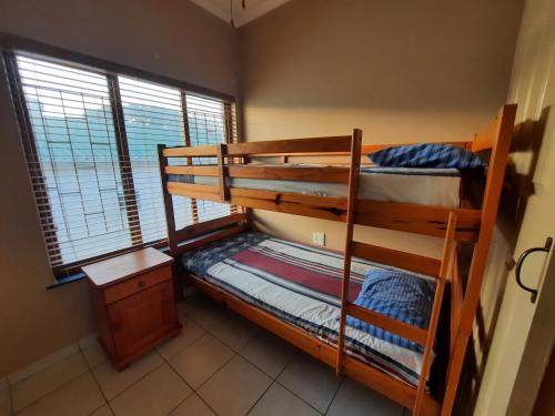 乌旺戈海滩Uvongo square Unit 24的带窗户的客房内的两张双层床