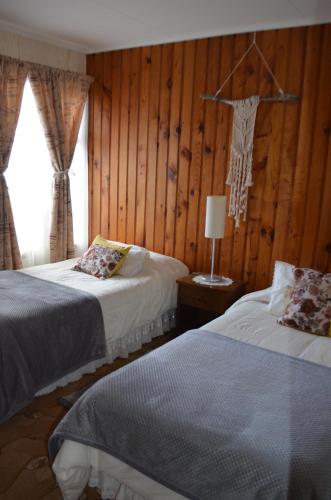 纳塔列斯港Hostal Los Pinos的木镶板客房内的两张床