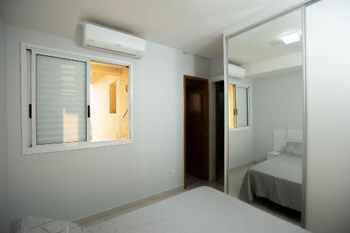 戈亚尼亚Apt moderno 3 suítes churrasqueira Goiânia的一间卧室配有镜子、一张床和一个窗户