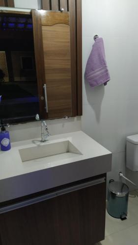 里奥迪孔塔斯Pousada Alto do Sossego的浴室水槽上方挂着紫色毛巾