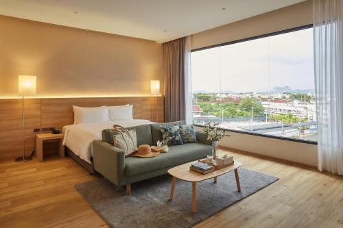拉差汶里HOTEL WISMA RATCHABURI的一间卧室配有一张床、一张沙发和一个大窗户