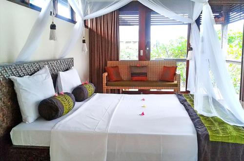 乌鲁瓦图杜克滨金别墅酒店的卧室配有带枕头的大型白色床