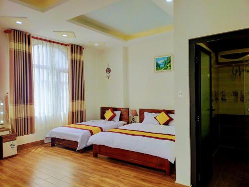 大叻NHÀ GÓC PHỐ Đà Lạt的一间卧室设有两张床和窗户。