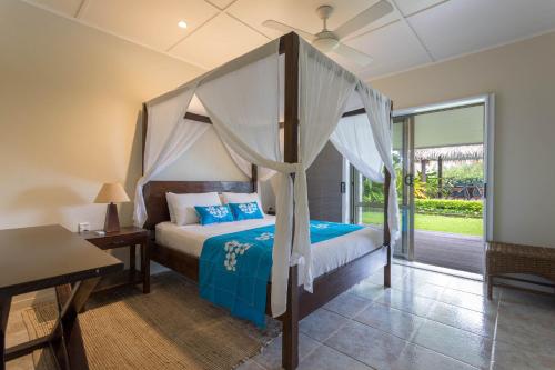 拉罗汤加穆里海滩别墅的一间卧室配有一张天蓬床和一张桌子