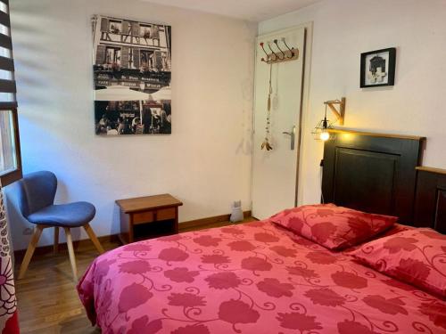希尔蒂盖姆Au Merlenchanteur的一间卧室配有红色的床和椅子