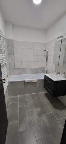 塔塔Dotis Apartman Tata的白色的浴室设有浴缸和水槽。