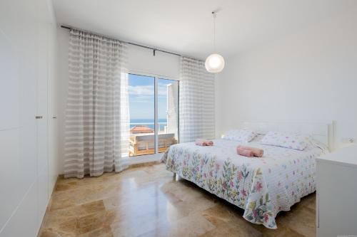 圣地亚哥港Residencial Playa de La Arena的白色的卧室设有床和大窗户