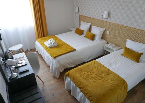 洛特河畔的维伦纽夫冰川酒店的酒店客房设有两张带黄床单的床和一张书桌